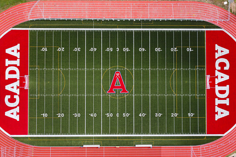 A straight down aerial view of the field, showing the artificial turf and Acadia branding.