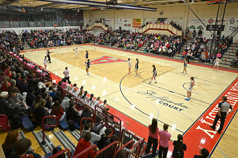 A well-attended women's basketball game, with the extensible bleachers largely full of spectators.